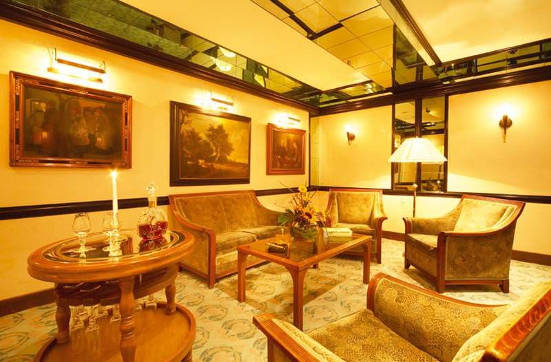 Art Nouveau Palace Hotel Praga Wnętrze zdjęcie The photo depicts a cozy and elegantly furnished lounge area. It features several comfortable chairs and a sofa, all arranged around a central wooden coffee table. A decorative arrangement of flowers sits on the table, adding a touch of color to the 