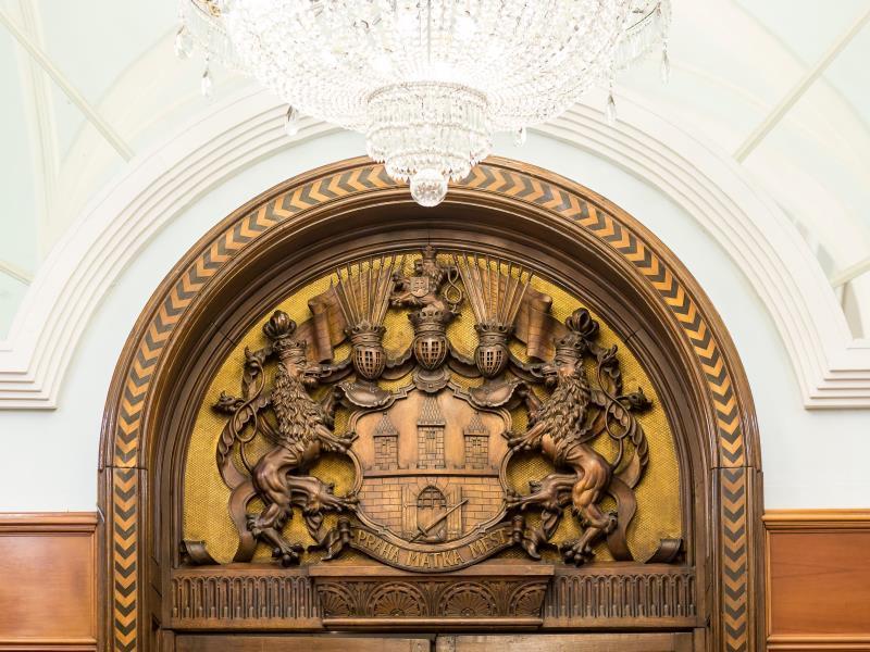 Art Nouveau Palace Hotel Praga Zewnętrze zdjęcie The photo depicts a beautifully crafted wooden archway with intricate carvings. At the center, there is a coat of arms, featuring two lions as supporters. Above the coat of arms, there are ornate decorative elements, possibly symbolizing authority or